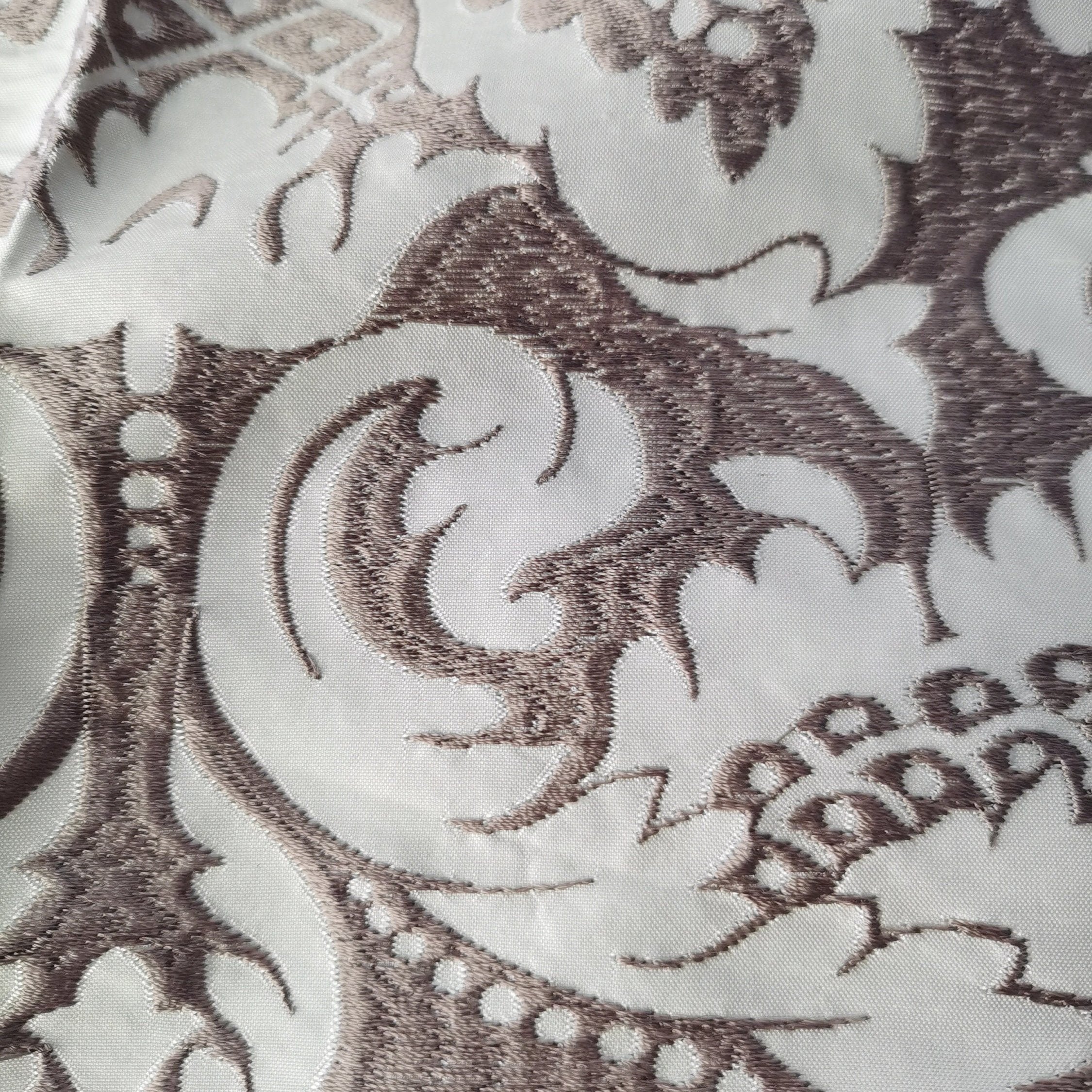 Elegant embroidered silk fabric designed for drapery and upholstery, featuring intricate floral motifs delicately stitched onto a soft, lustrous silk background. The luxurious texture and flowing quality of the fabric create a refined, graceful look.